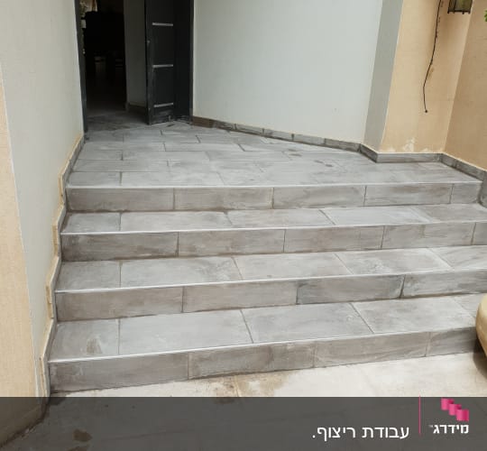 מדרגות מרוצפות באריחים אפורים בכניסה לבית